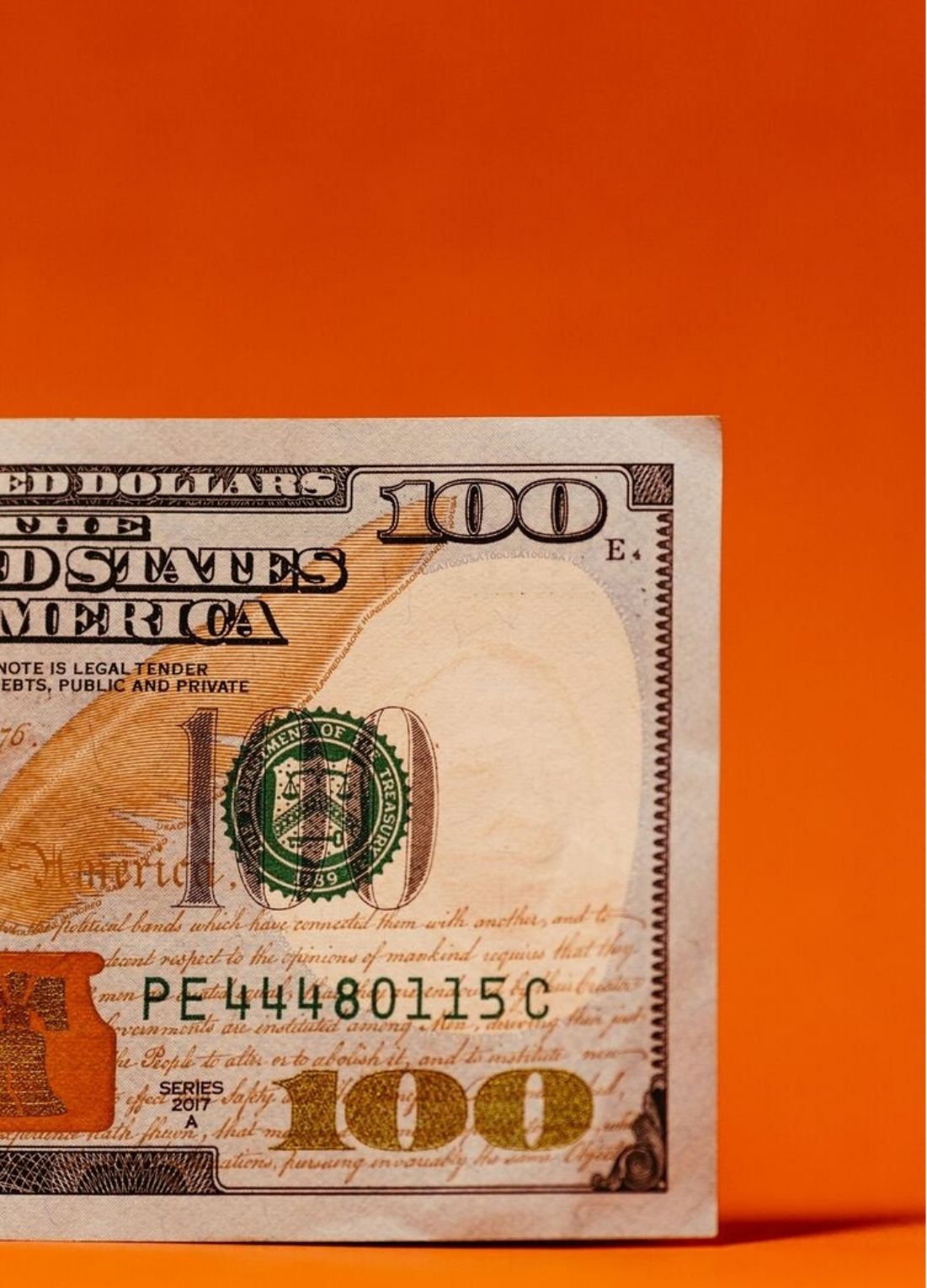 A one hundred dollar bill on an orange background